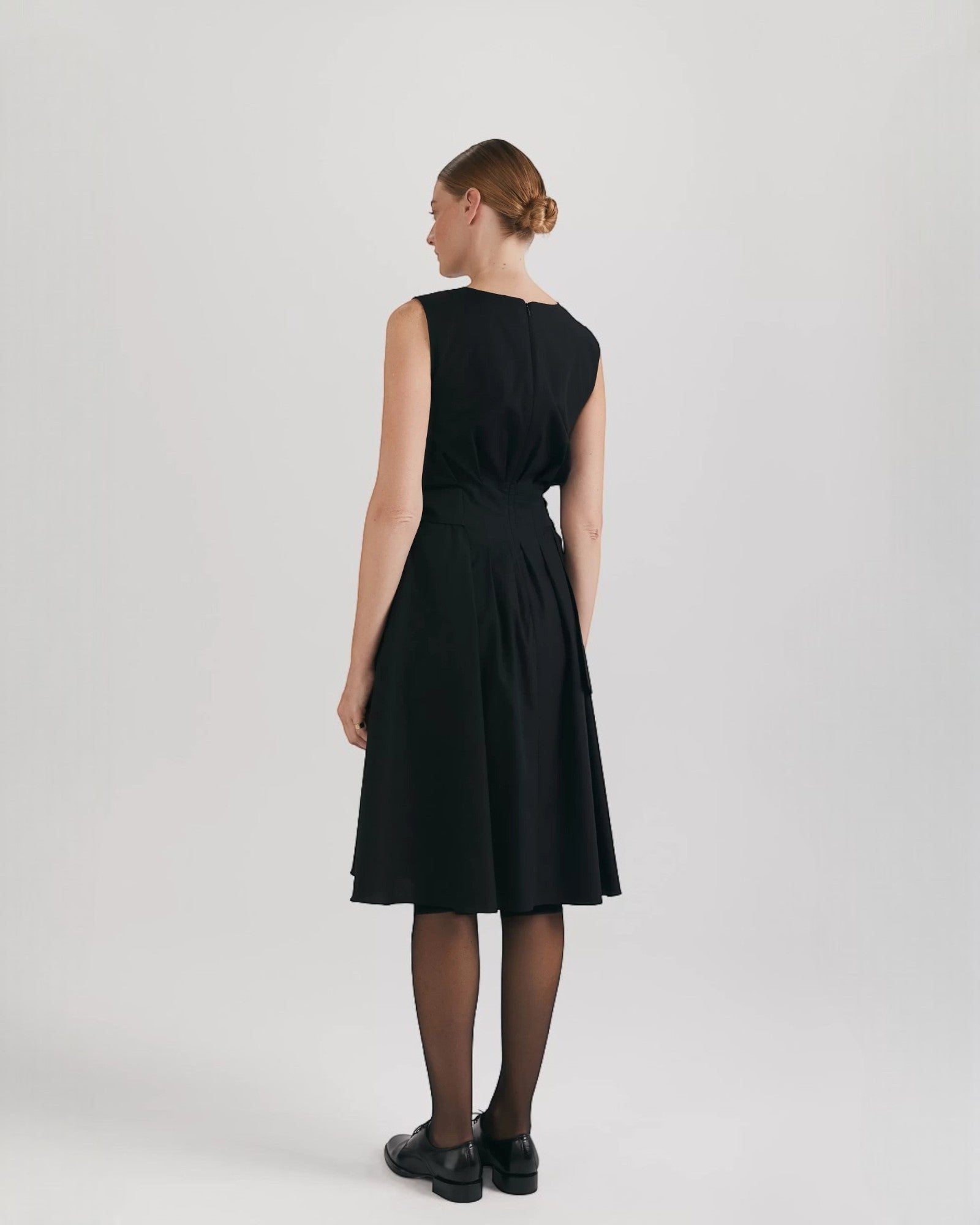 Ipanomi black organic cotton midi dress with pleats, hidden pockets, and a flared skirt.