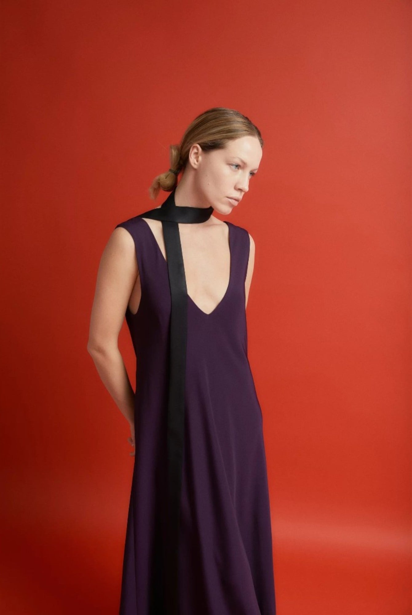 Ipanomi narrow black silk scarf worn as a necktie with a deep V-neck purple dress.