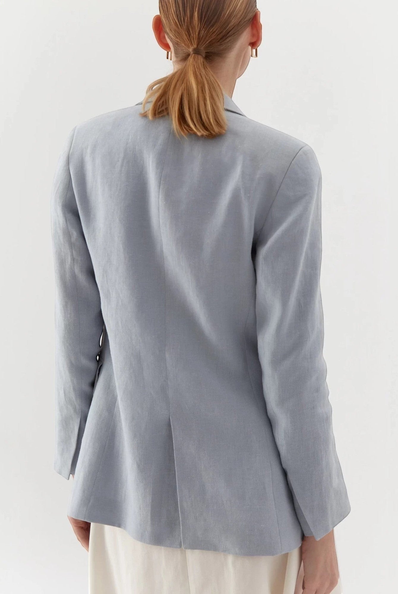 Ipanomi light blue linen blazer, tailored fit, no buttons, with flap pockets. Model from back.