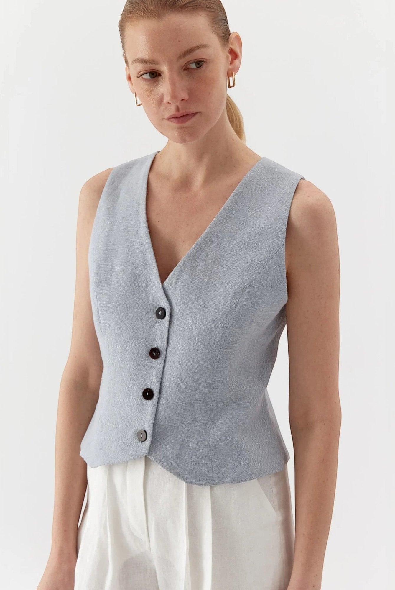 Ipanomi light blue pure linen short vest with V-neck and contrast buttons. Model wears size S.