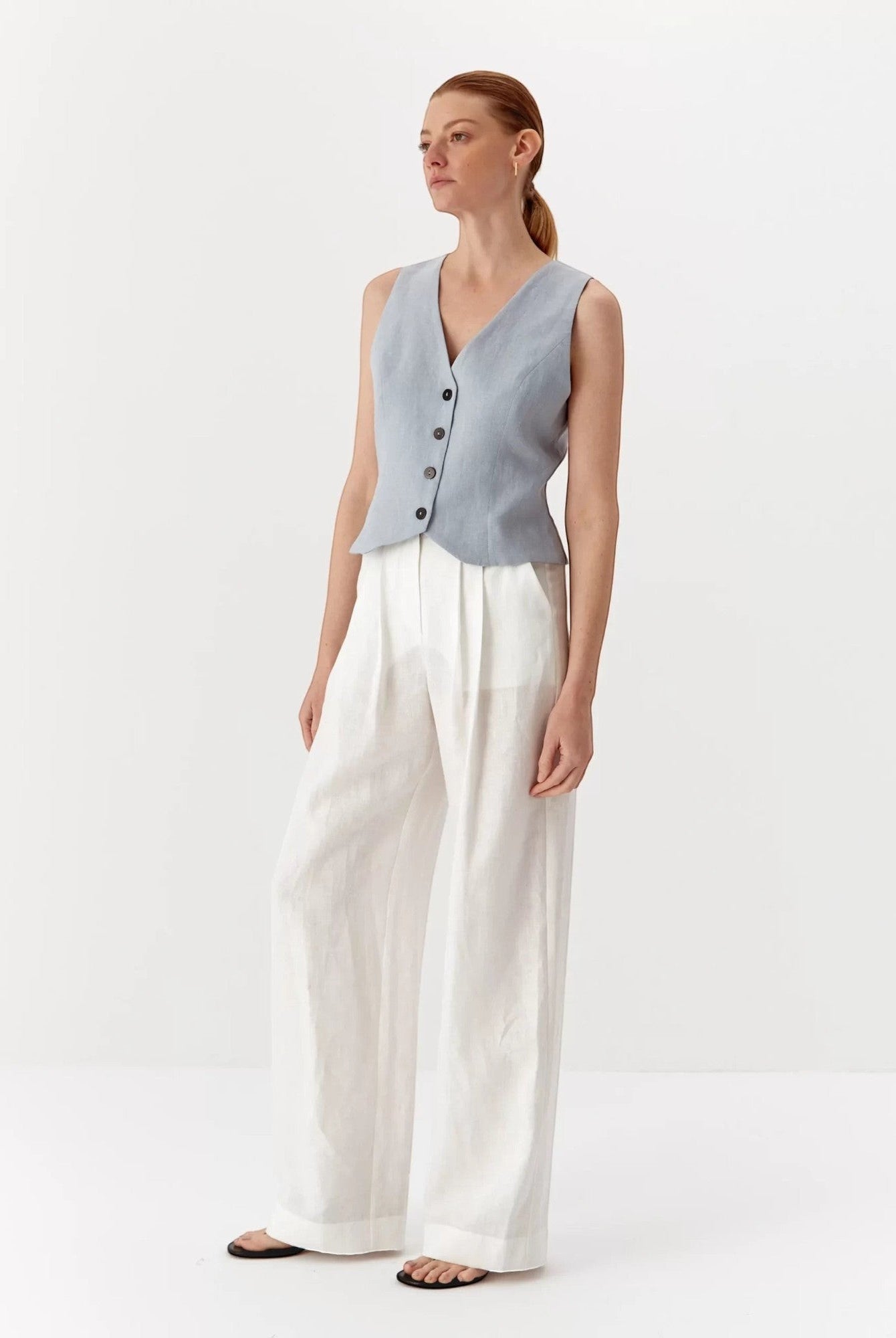 Ipanomi light blue pure linen short vest with V-neck and contrast buttons, worn by a model.