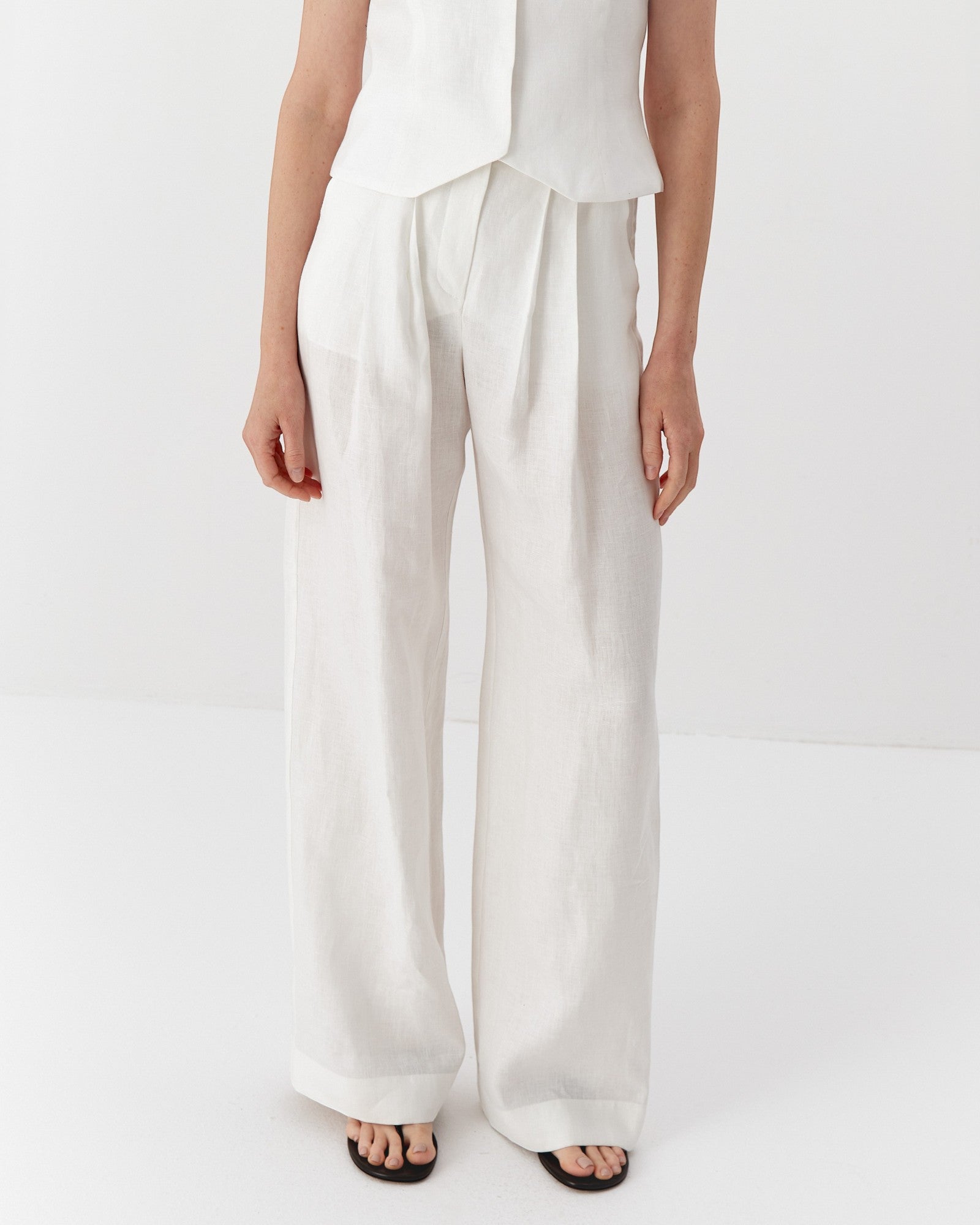 Ipanomi white hemp wide-leg trousers with double pleats, high waist, and side pockets.