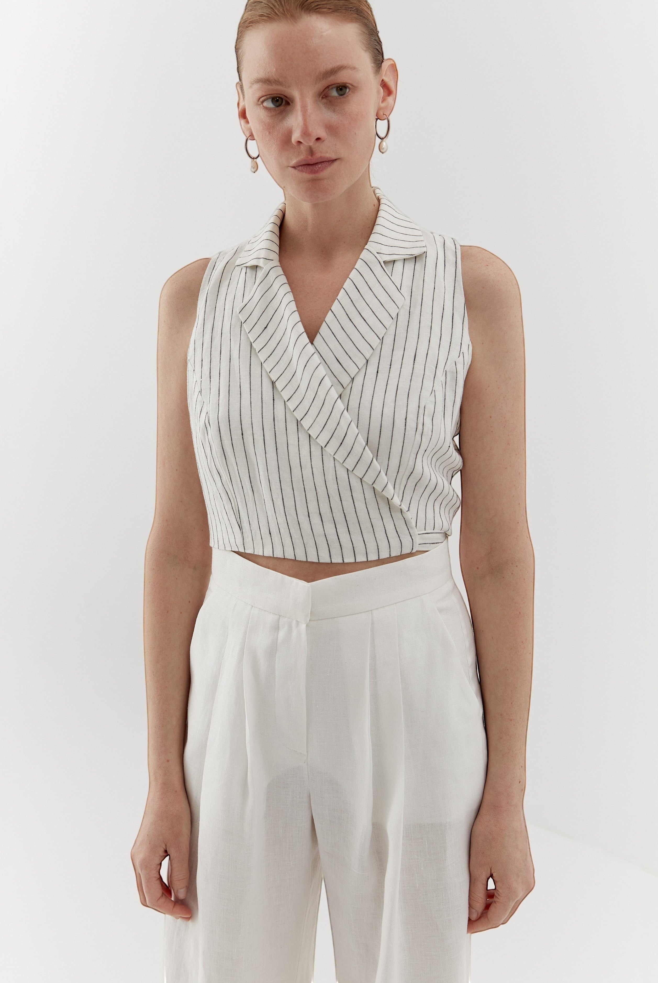 Ipanomi white linen vest with fine black pinstripes, featuring a wrap front and lapel collar.