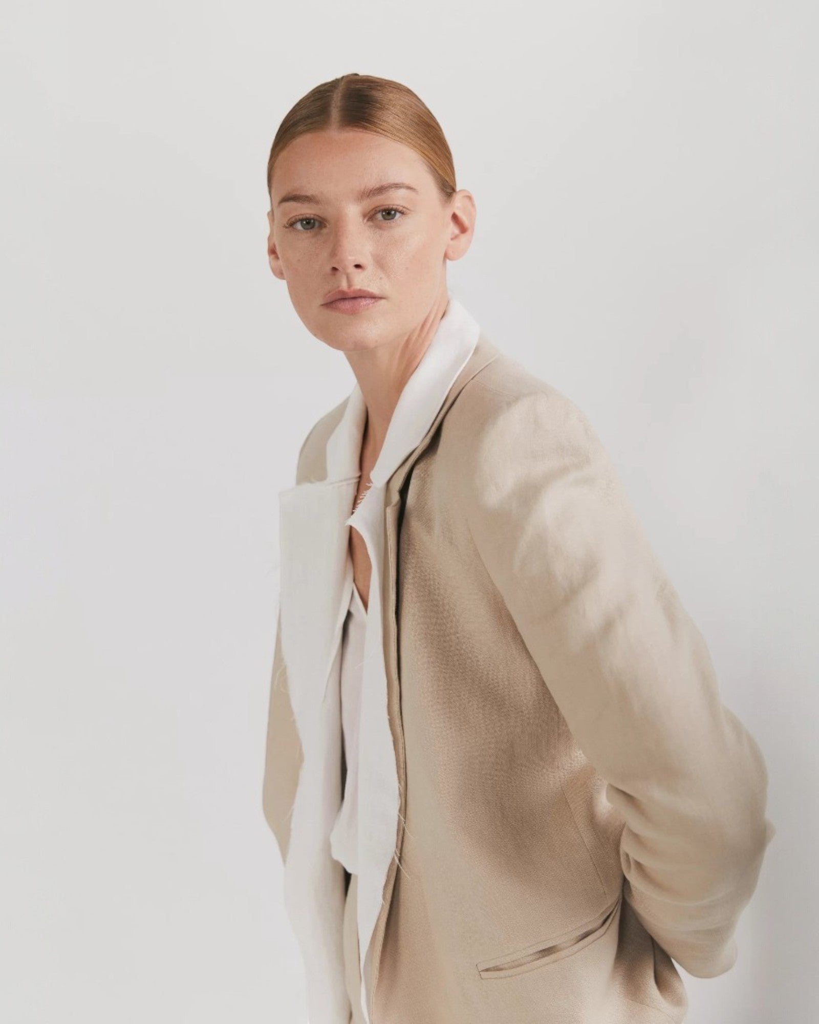 Ipanomi beige linen long blazer with lapel collar, no buttons, and front pockets. Features a detachable accessory and cotton lining.