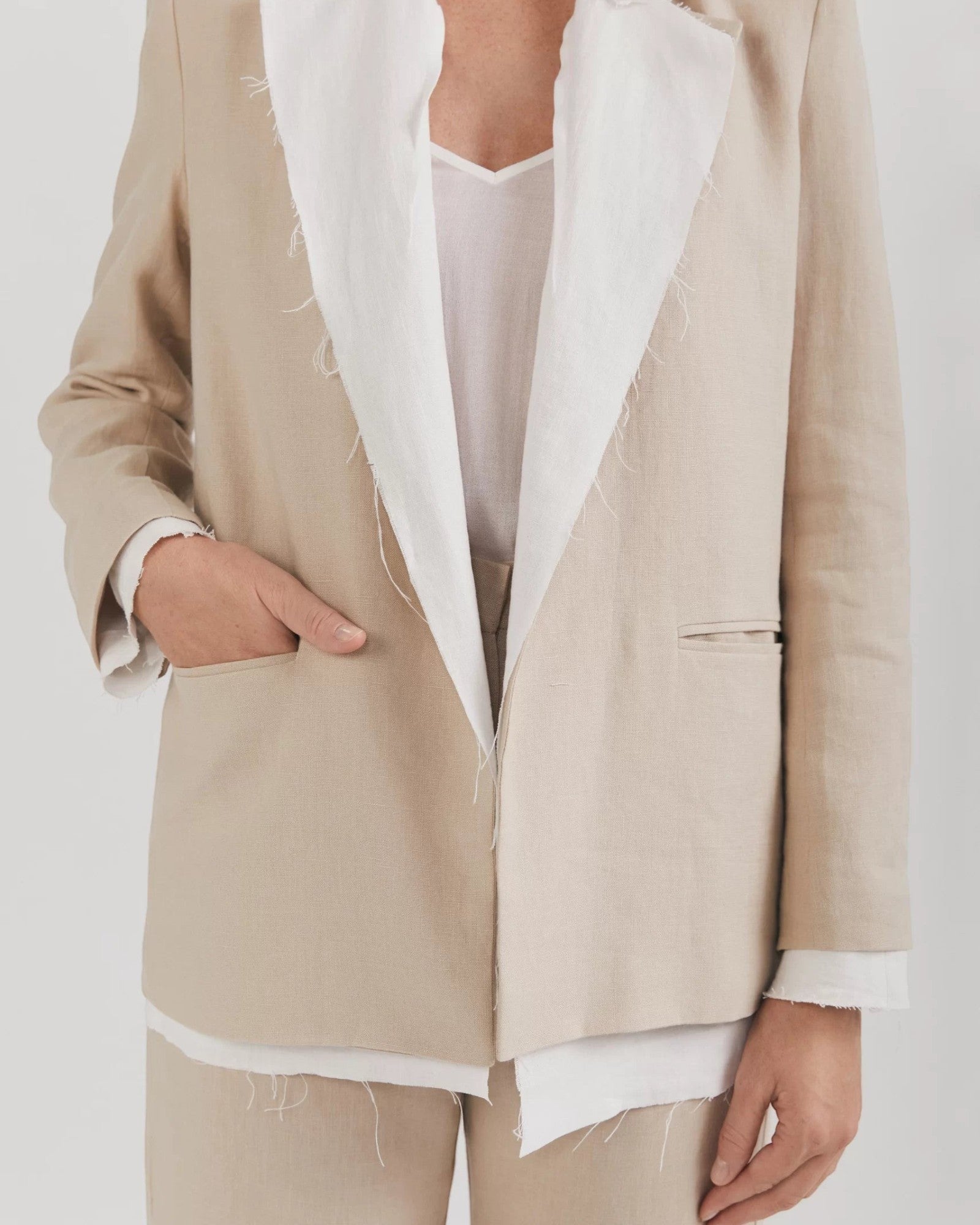 Ipanomi beige linen blazer with white frayed lapels, no buttons, and a feminine cut. Features cotton lining and flap pockets.