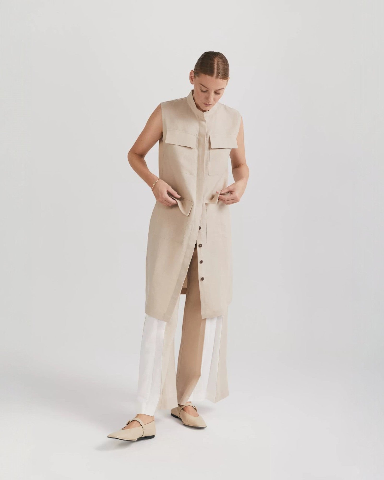 Ipanomi beige linen midi dress with mandarin collar, button front, and cargo pockets. Sleeveless design can be worn as a vest.