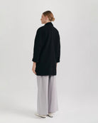 Ipanomi black oversized wool jacket with scarf collar and invisible snap closure.