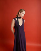 Ipanomi narrow black silk scarf worn as a necktie with a deep V-neck purple dress.