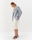 Ipanomi light blue linen blazer with lapel collar, no buttons, and flap pockets. Model is wearing size S.