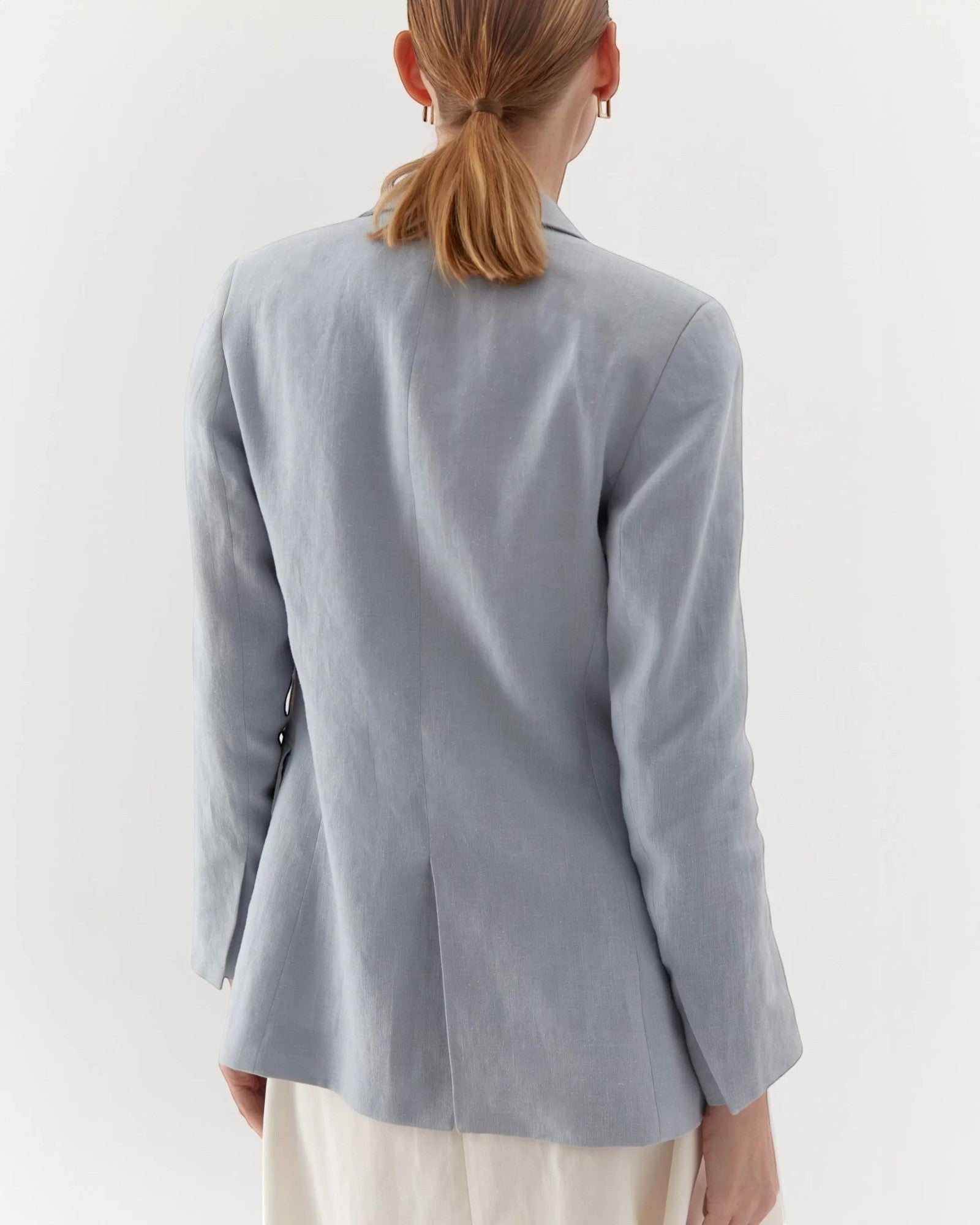 Ipanomi light blue linen blazer, tailored fit, no buttons, with flap pockets. Model from back.