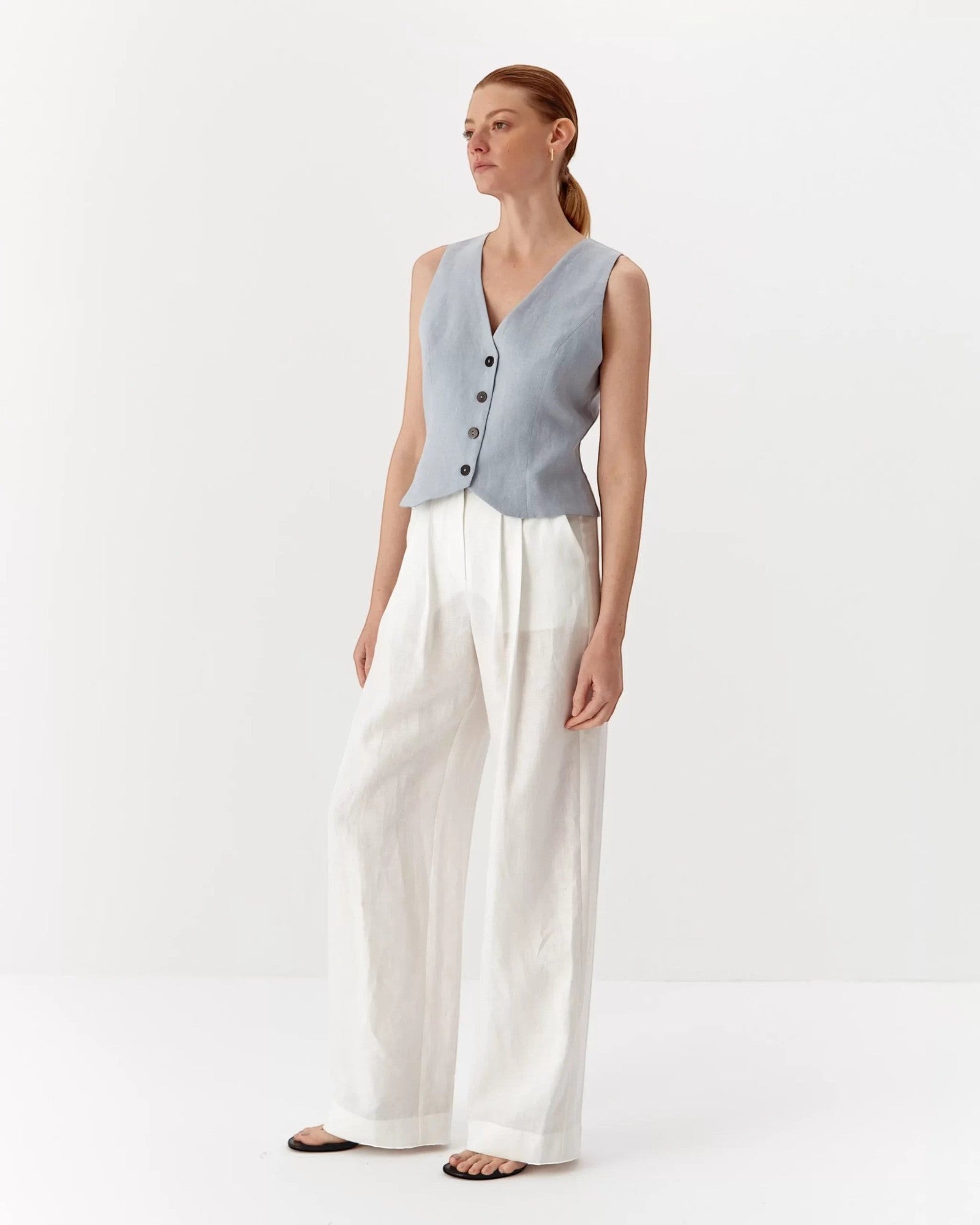 Ipanomi light blue pure linen short vest with V-neck and contrast buttons, worn by a model.