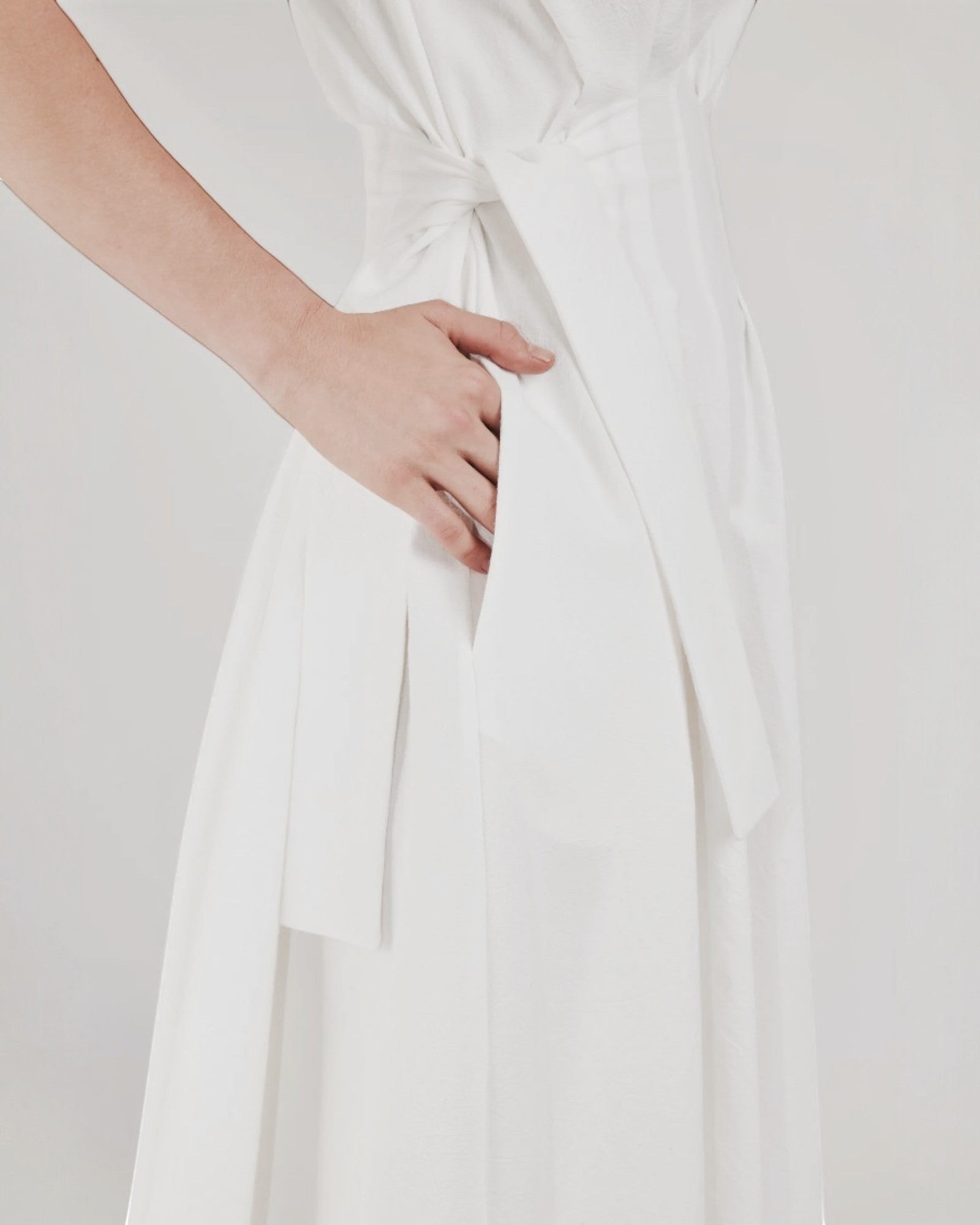 Ipanomi white cotton midi dress with adjustable waist tie, pleats, and hidden side pockets. Sleeveless design.