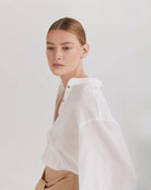 Ipanomi white cotton voile long shirt with balloon sleeves, mandarin collar, and side slits. Button-up front.