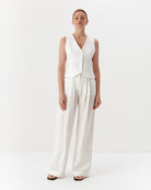 Ipanomi white hemp wide-leg trousers with double pleats and side pockets, worn by a model.