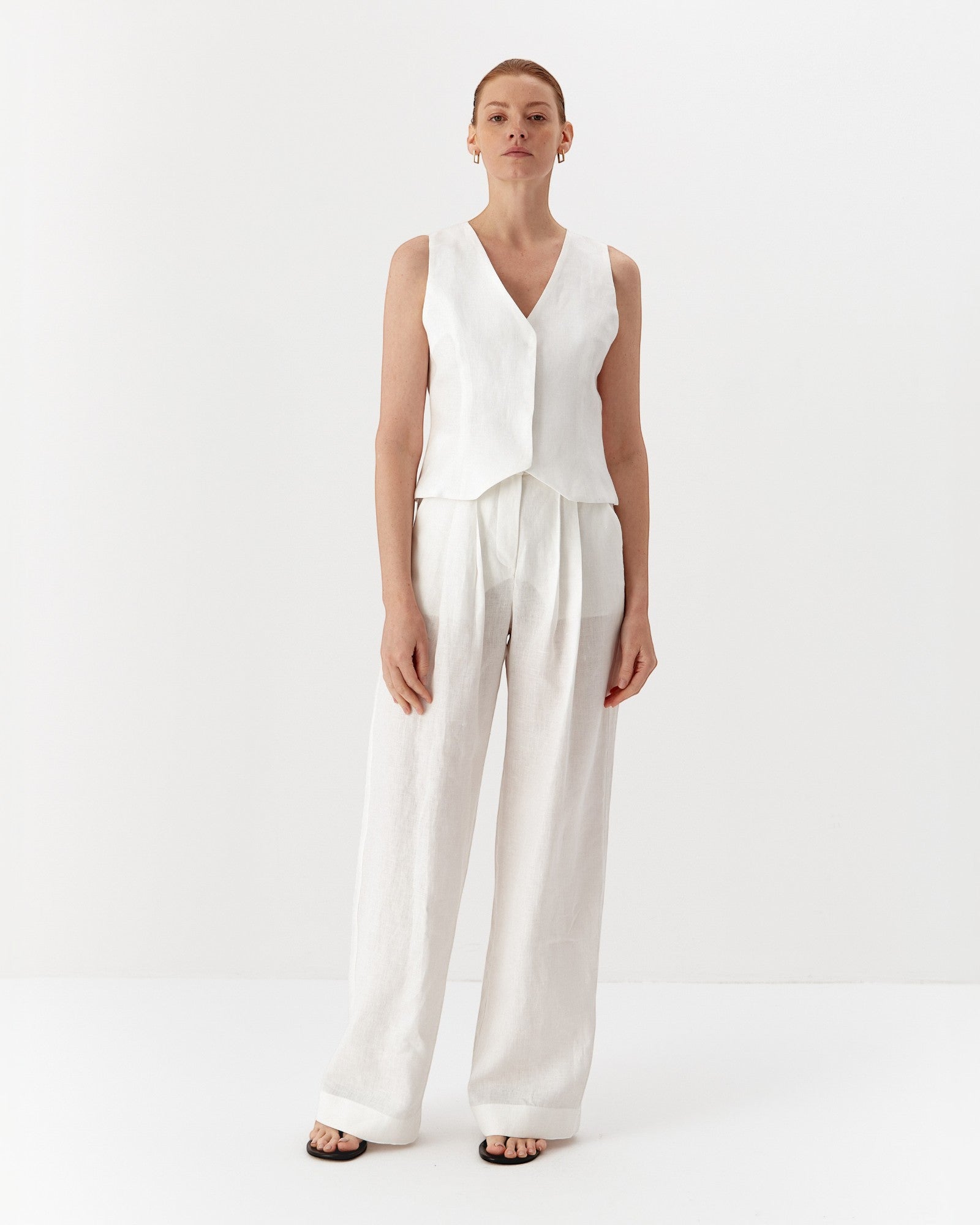 Ipanomi white hemp wide-leg trousers with double pleats and side pockets, worn by a model.