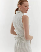 Ipanomi white linen trousers with black pinstripes, high waist, straight leg, and tie waist. Model wears size S.