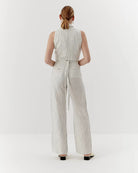 Ipanomi white linen trousers with black pinstripes, high waist, straight leg, and tie belt. Model is wearing size S.
