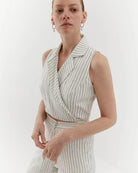Ipanomi white linen trousers with black pinstripes, high-waisted, straight leg, and side pockets. Model wears size S.