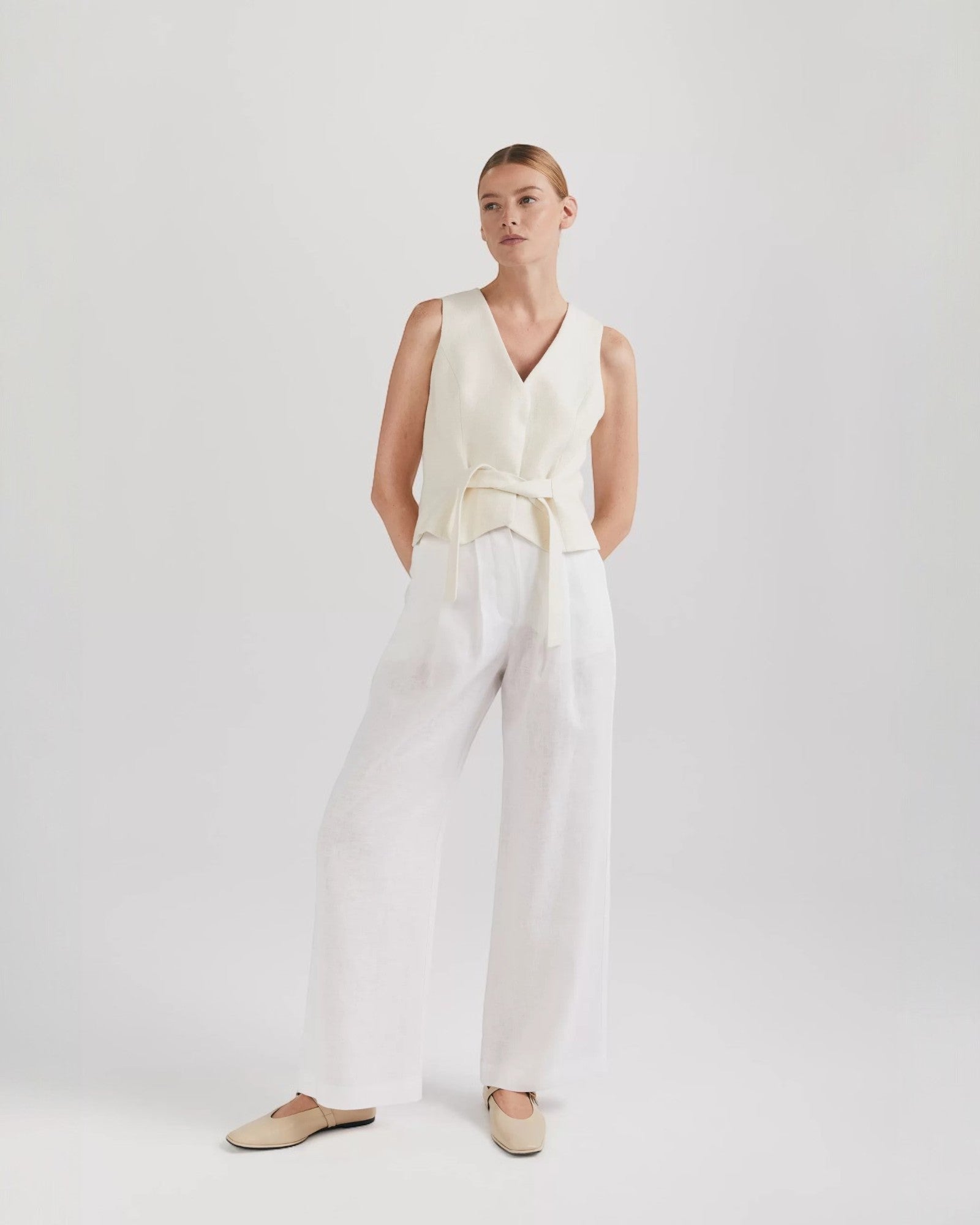 Ipanomi white linen wide-leg trousers with double pleats, side slant pockets, back pockets, and zip closure.