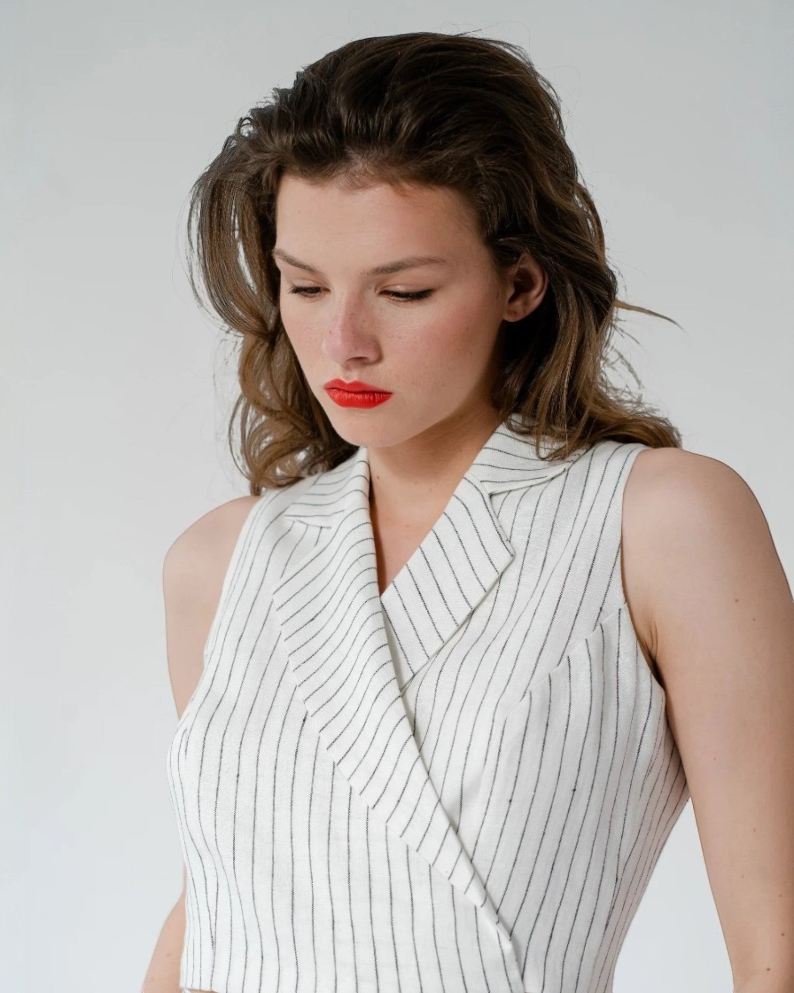 Ipanomi white sleeveless pinstripe blazer-style crop top with a V-neck and lapel collar.
